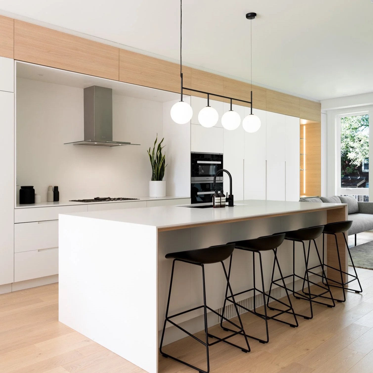Coastal Contemporary Linear Kitchen System, Toronto. Linear shaped floor-to-ceiling white kitchen cabinetry with integrated handles, white Caesarstone quartz kitchen island, integrated Miele appliances, and office nook with integrated lighting.