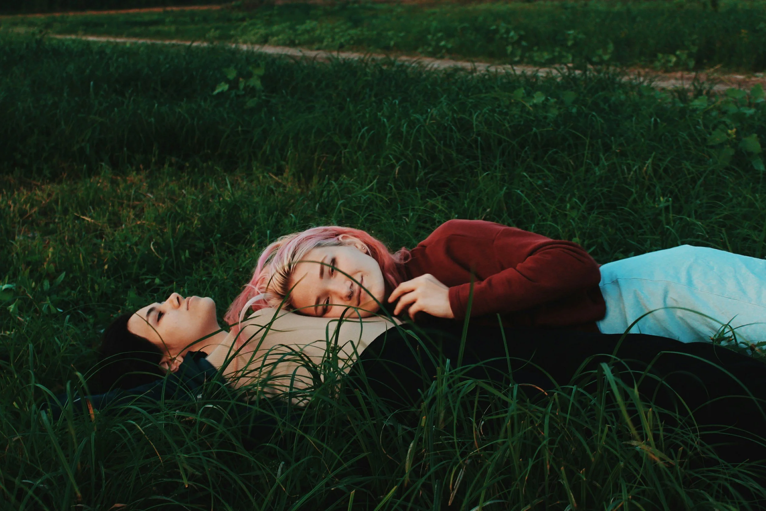 two young women lying intimately in grass