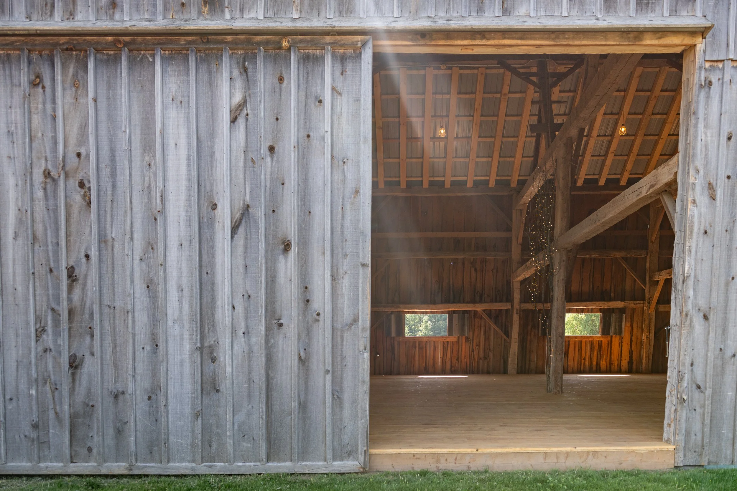 Open rustic barn with wooden interior and two small windows.