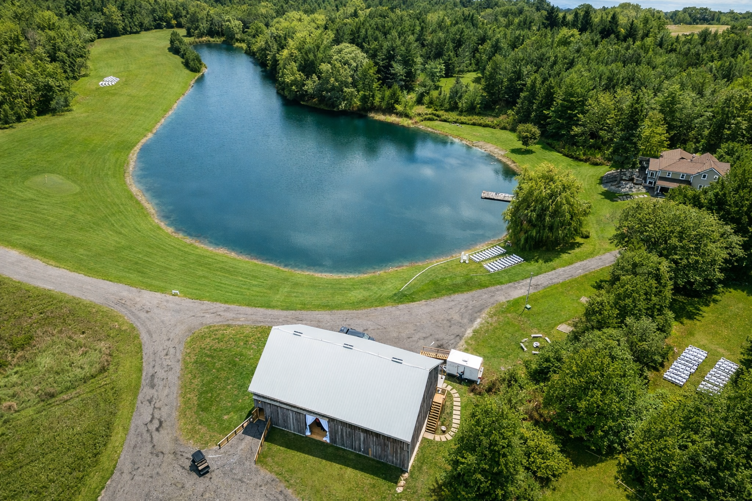 An aerial view of The Hummingbird wedding venue in Erin, Ontario, showcasing the restored heritage barn, private pond, and expansive countryside grounds. The property offers a secluded and scenic setting for weddings and intimate celebrations.
