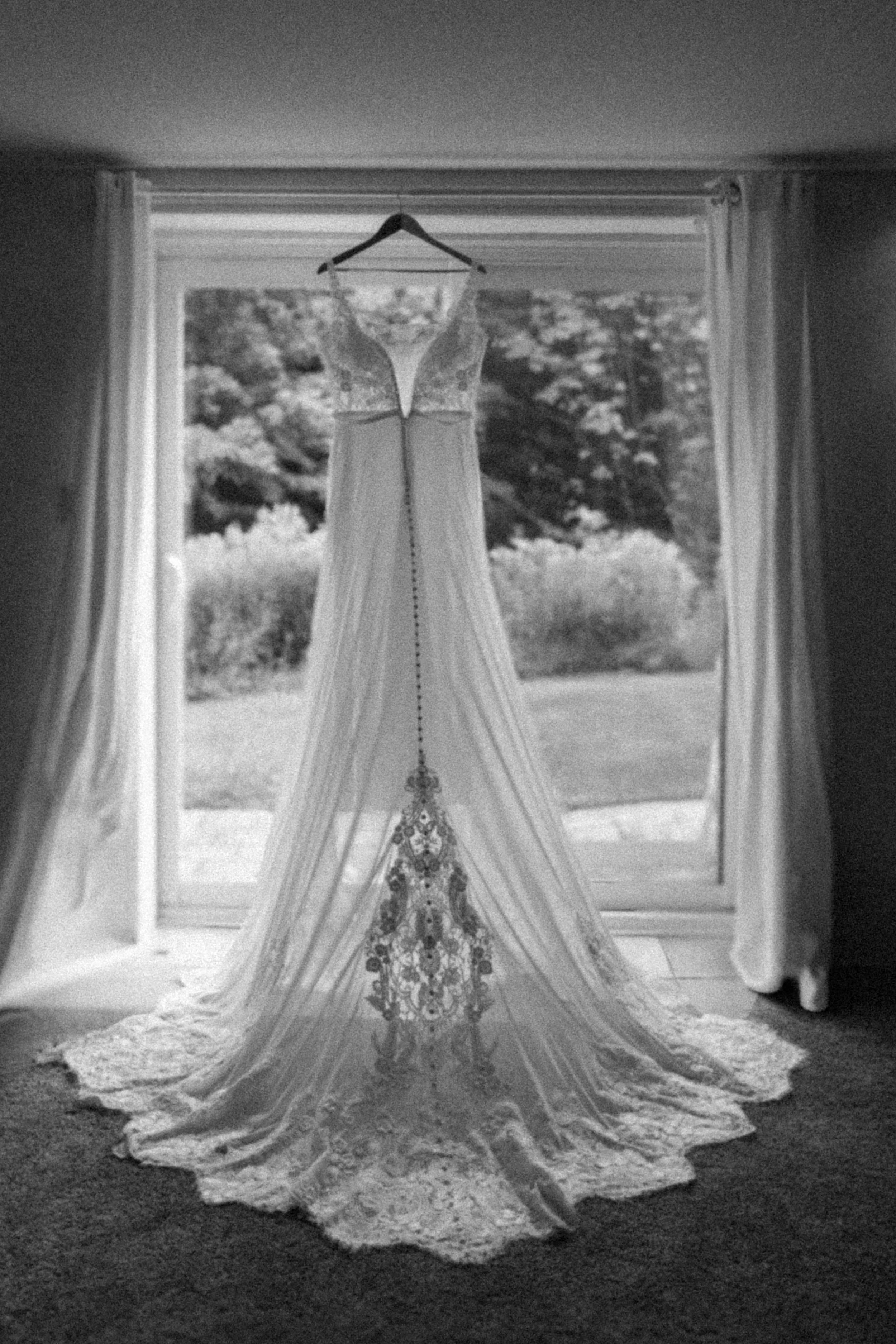 Bridal wedding dress hanging in soft natural light at The Hummingbird in Erin, Ontario, showcasing elegant lace details and timeless bridal style in a serene countryside setting.