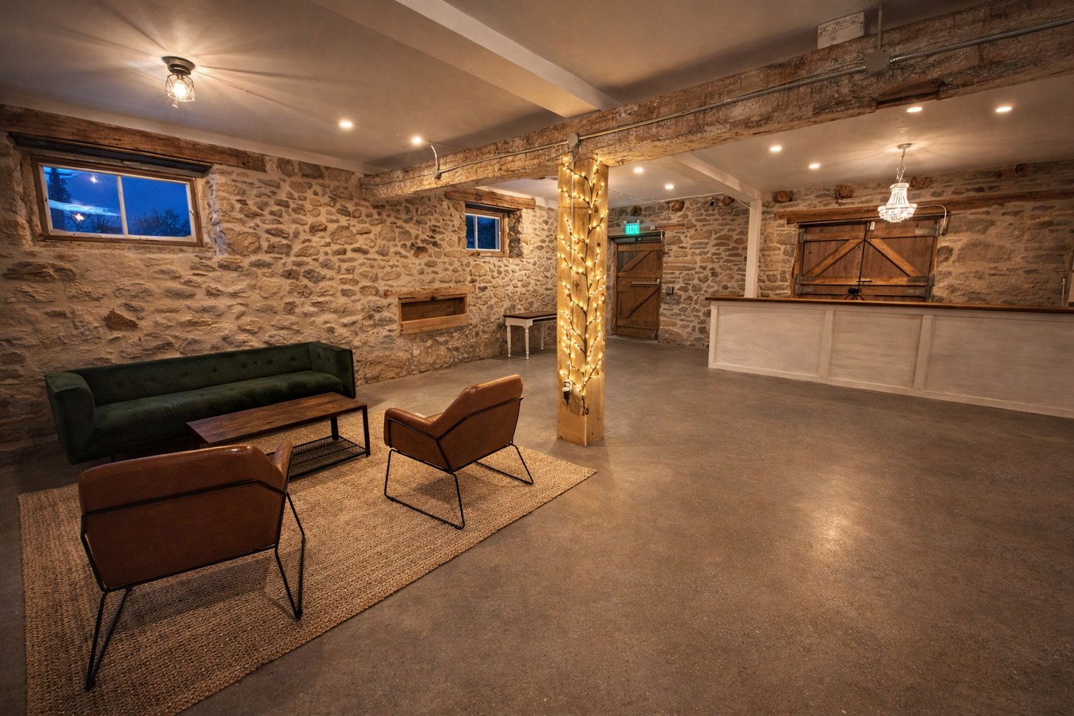 A thoughtfully designed lounge space at The Hummingbird in Erin, Ontario, showcasing original stone walls, cozy seating, and warm ambient lighting. Located on the lower level of the heritage barn, this relaxed gathering area provides a comfortable pl