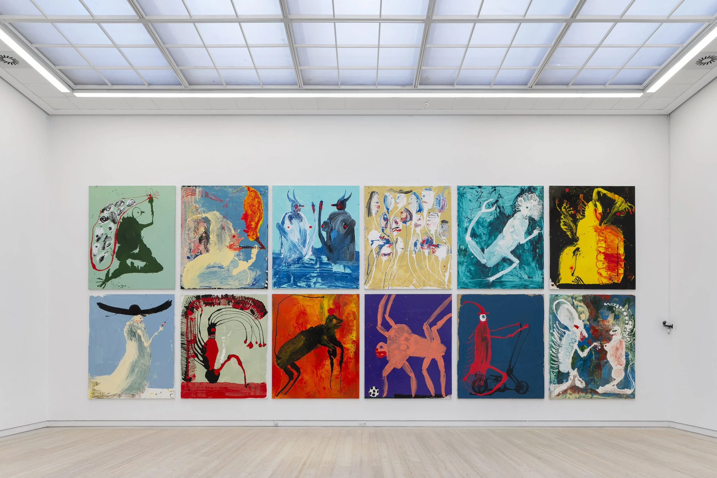 A gallery wall displays two rows of ten colorful abstract paintings with various figures and creatures on a white wall, with a skylight ceiling above. Frederik Næblerød Time to Move exhibition at  Horsens Art museum Kunstmuseum, Denmark.