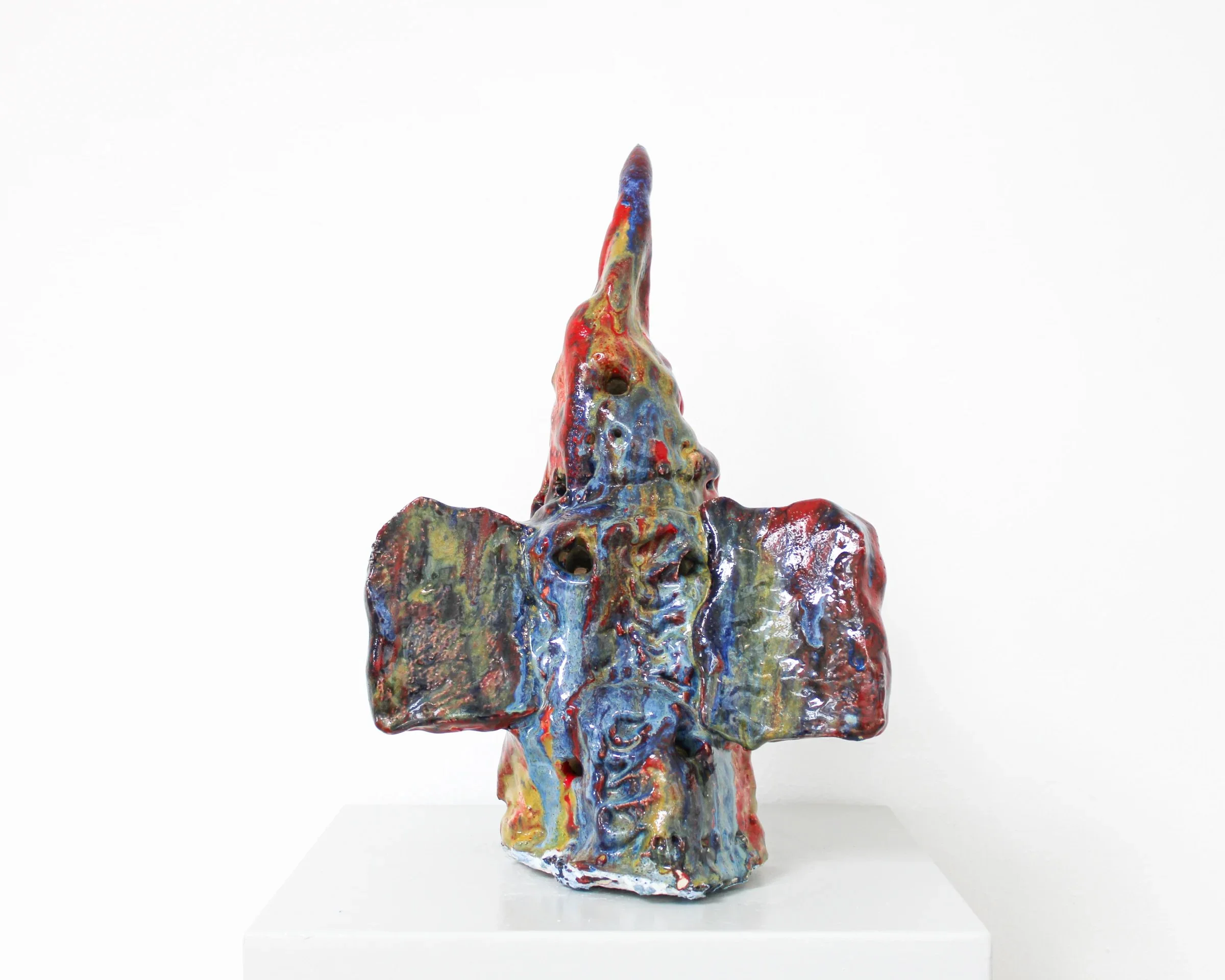 Colorful abstract ceramic sculpture with a pointed top, mounted on a white pedestal against a plain white background. Frederik Næblerød exhibition at Alice Folker Gallery, Denmark.