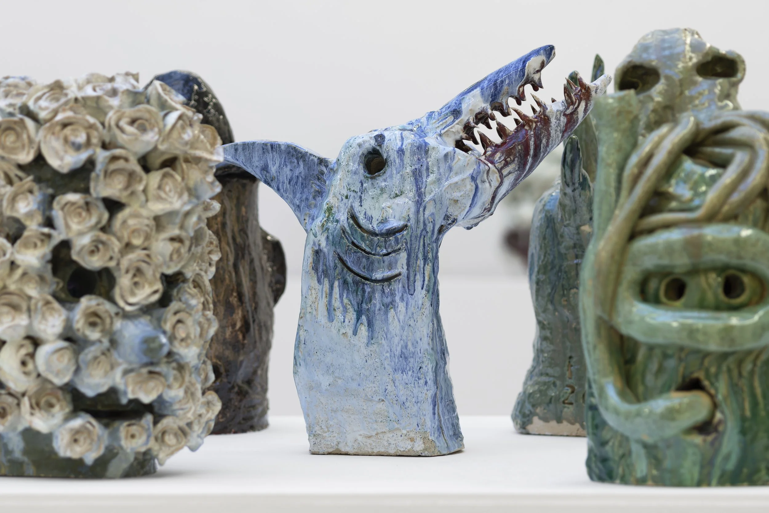 Ceramic sculptures including a smiling blue and white dog with a long snout, and other abstract faces and figures. Frederik Næblerød Time to Move exhibition at  Horsens Art museum Kunstmuseum, Denmark.