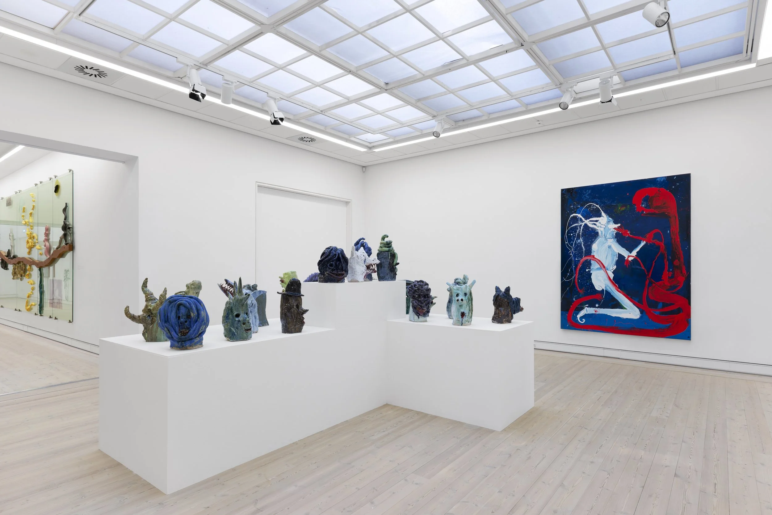Art gallery with sculptures on white display stands and a large colorful painting on the wall. Frederik Næblerød Time to Move exhibition at  Horsens Art museum Kunstmuseum, Denmark.