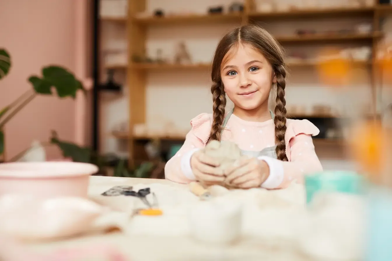a happy child playing with clay as part of her art therapy session in Singapore
