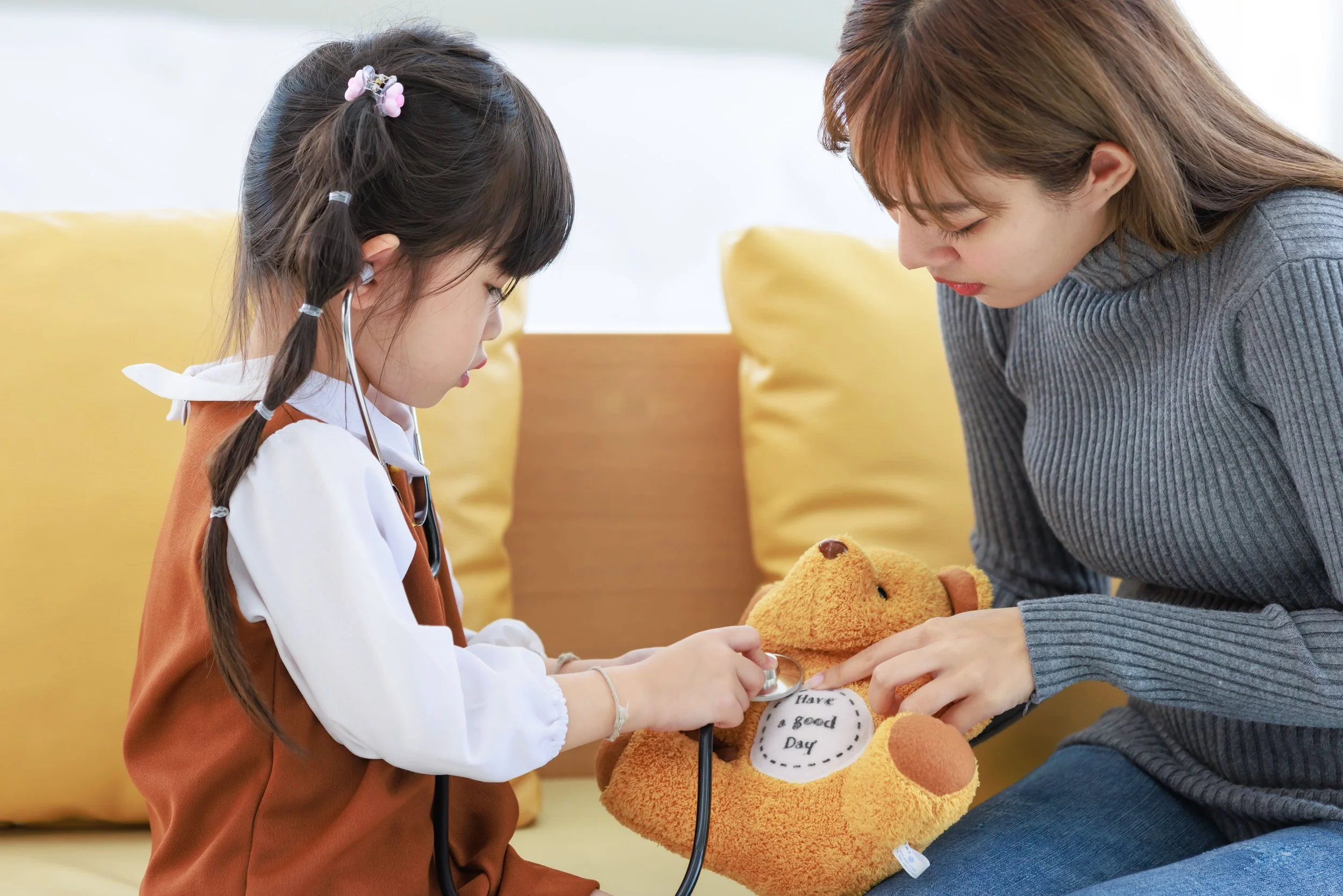 little asian girl playing with her teddy bear using a stethoscope