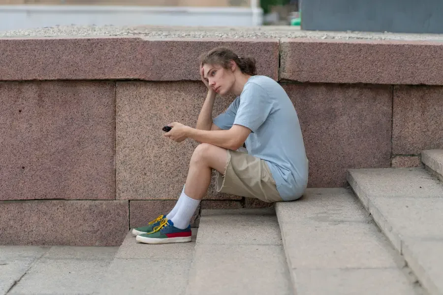a young teenager sitting on the stairs, having no interest in doing his hobbies and in need of help from a teenager psychologist