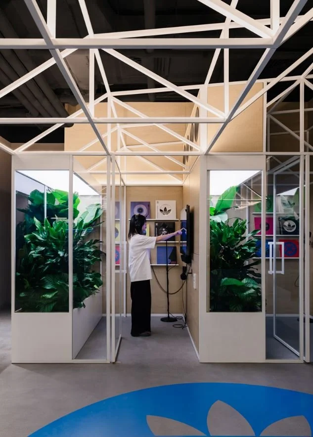 Interactive try-on and experience booth inside the Adidas Flagship Sanlitun Beijing with structural frame and planted surroundings.