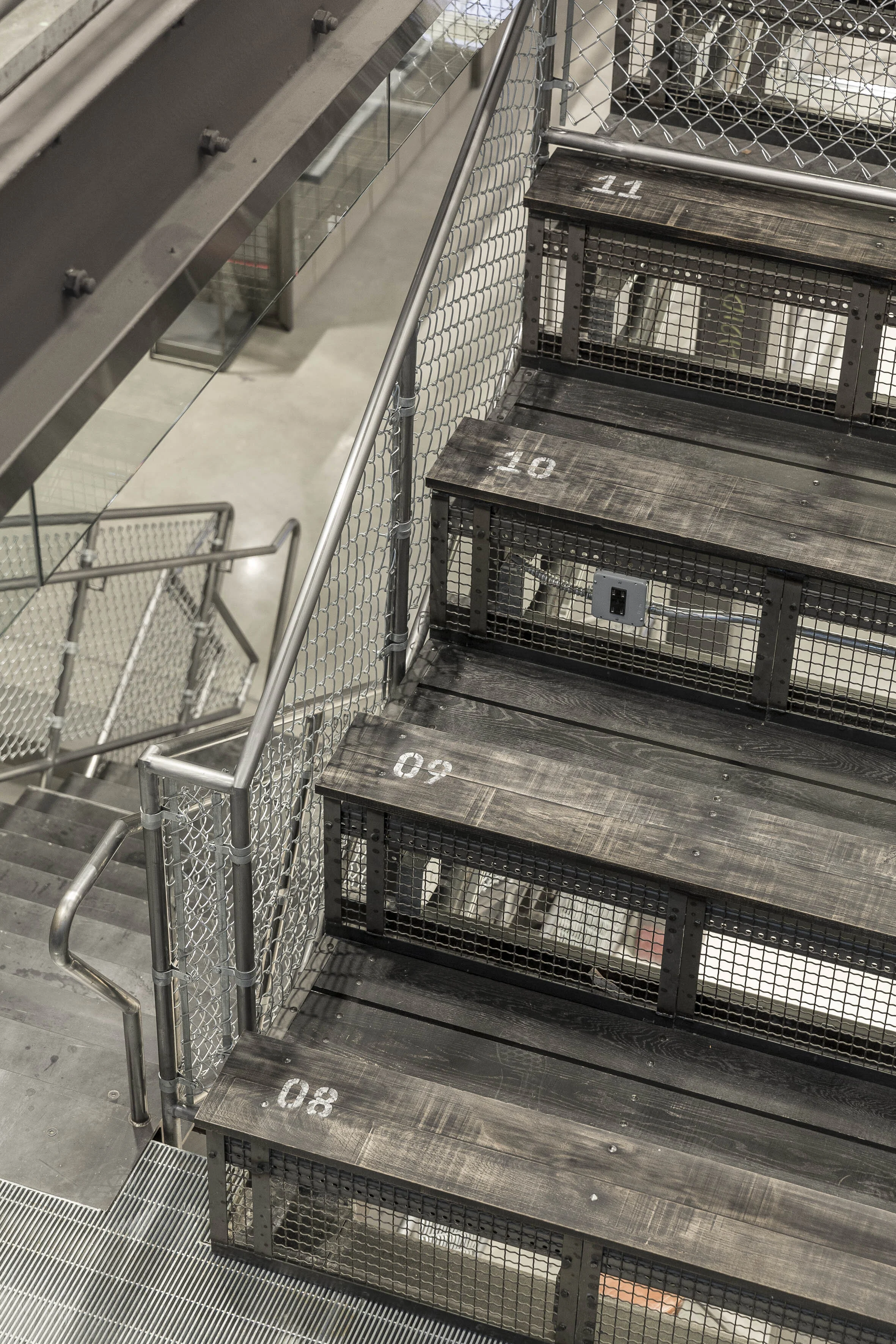 Industrial staircase detail inside Adidas Flagship NYC with steel mesh and numbered steps