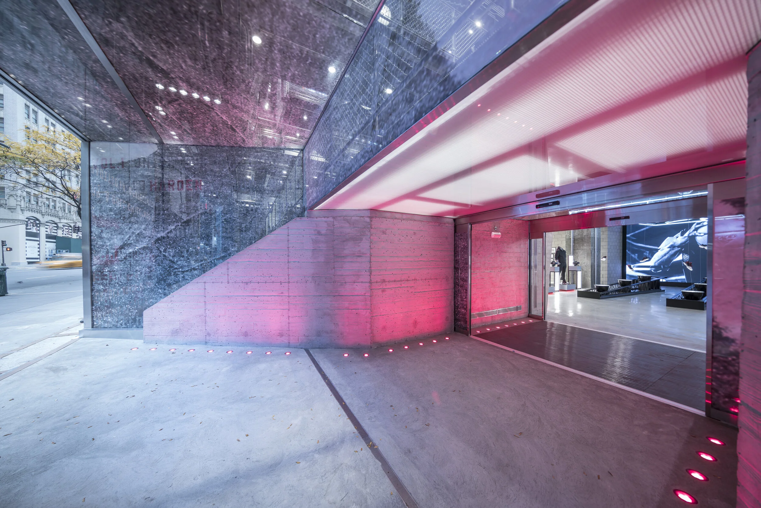 Adidas Flagship NYC exterior featuring illuminated glass entrance and concrete architecture