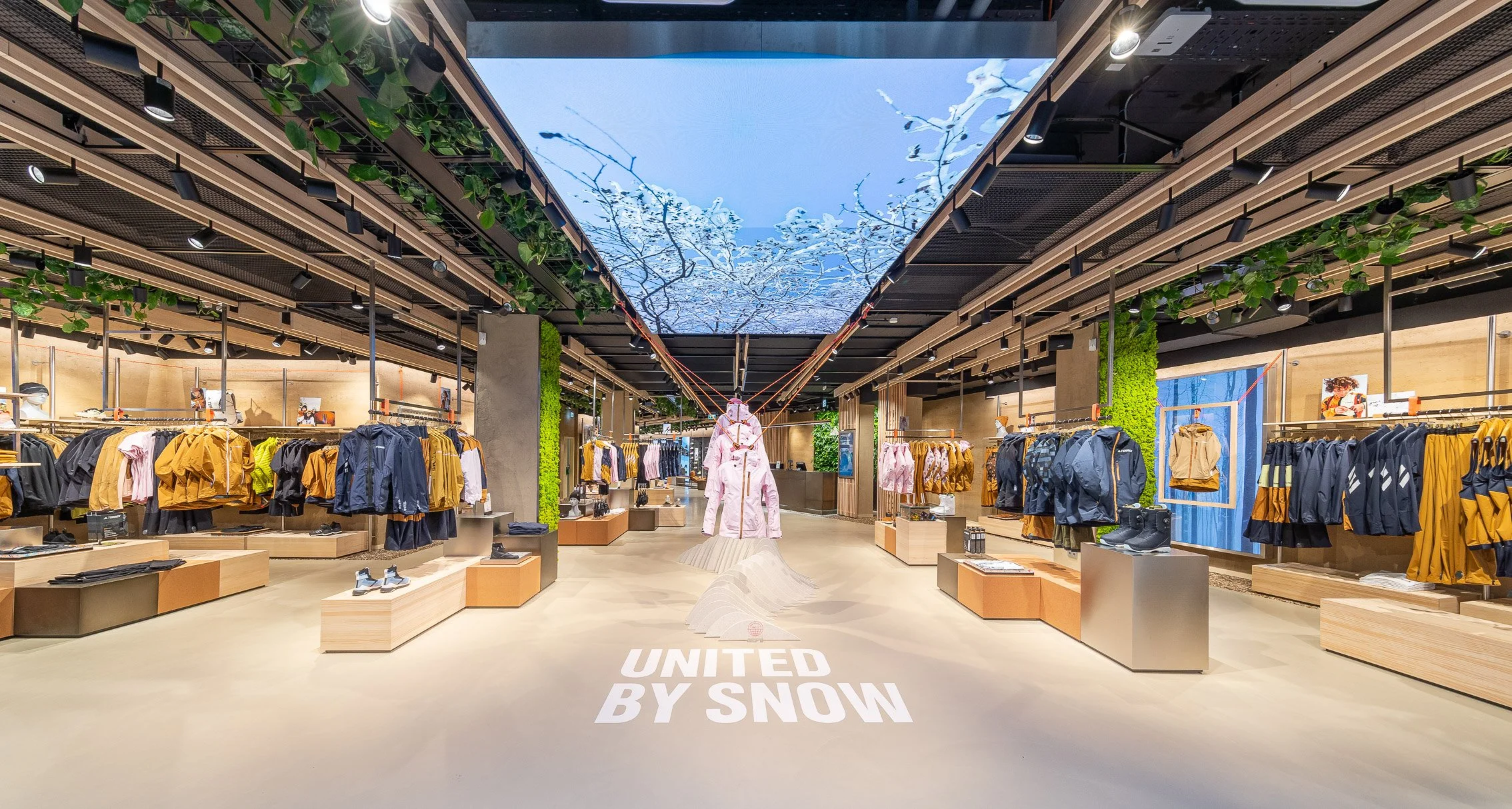 Immersive Adidas Terrex Munich retail interior showcasing the United by Snow campaign, with suspended outerwear, nature-inspired ceiling installation, and outdoor performance apparel displays.