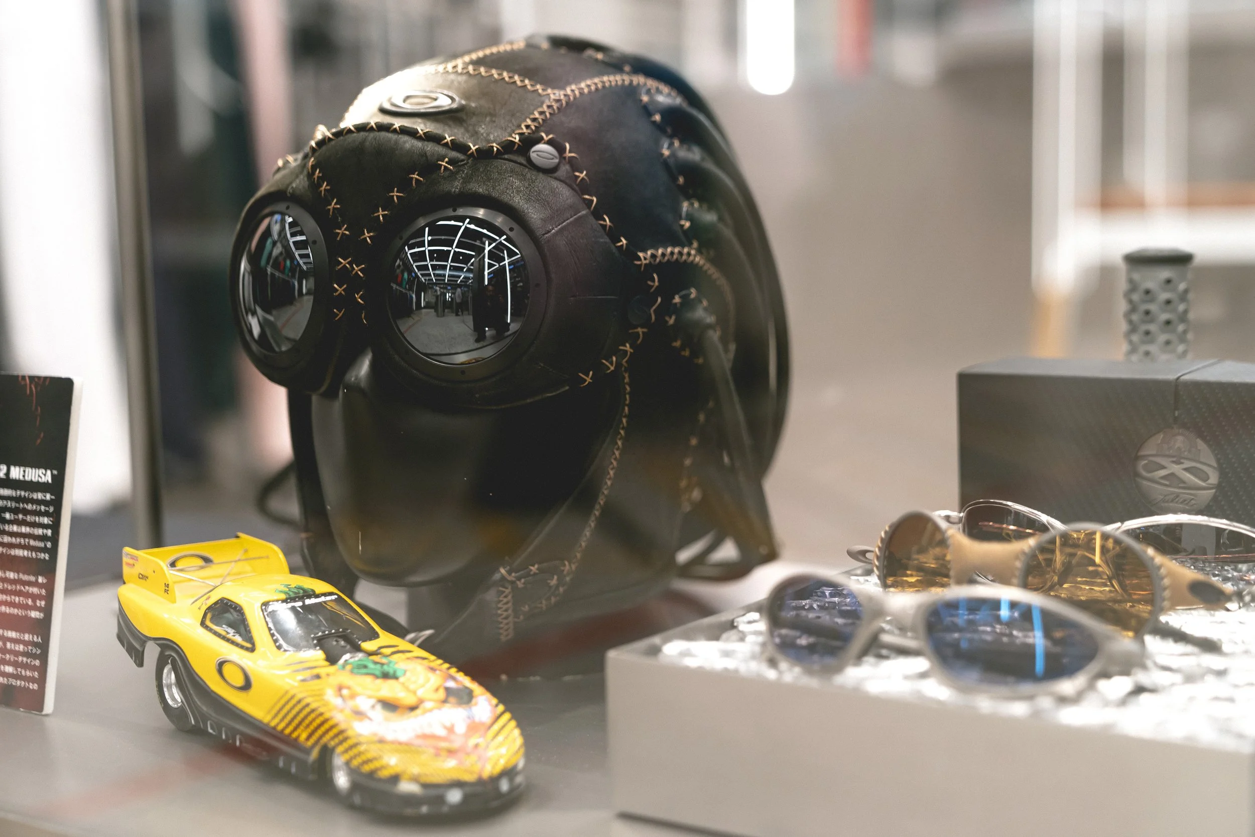 Oakley flagship store Shibuya Japan product display concept featuring experimental helmet form, goggles, and collectible objects in a glass vitrine.