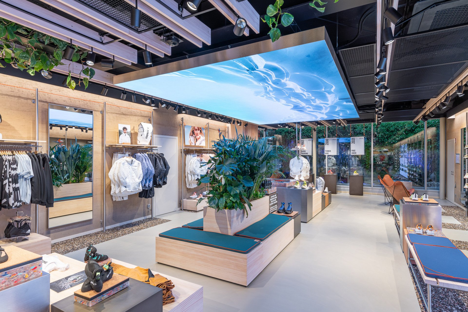 Sustainable Adidas Terrex Munich retail interior with integrated plants, timber fixtures, and ceiling LED nature visuals.