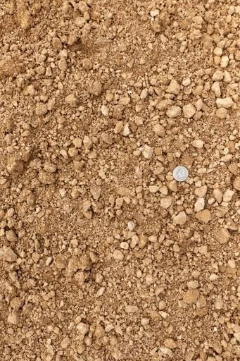 Close-up of fine gravel or crushed stone with a coin for scale.