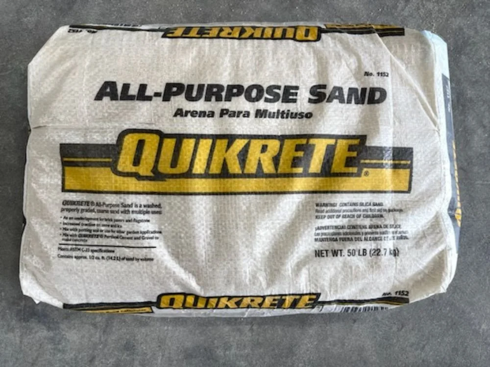 A bag of Quikrete All-Purpose Sand placed on a concrete surface.