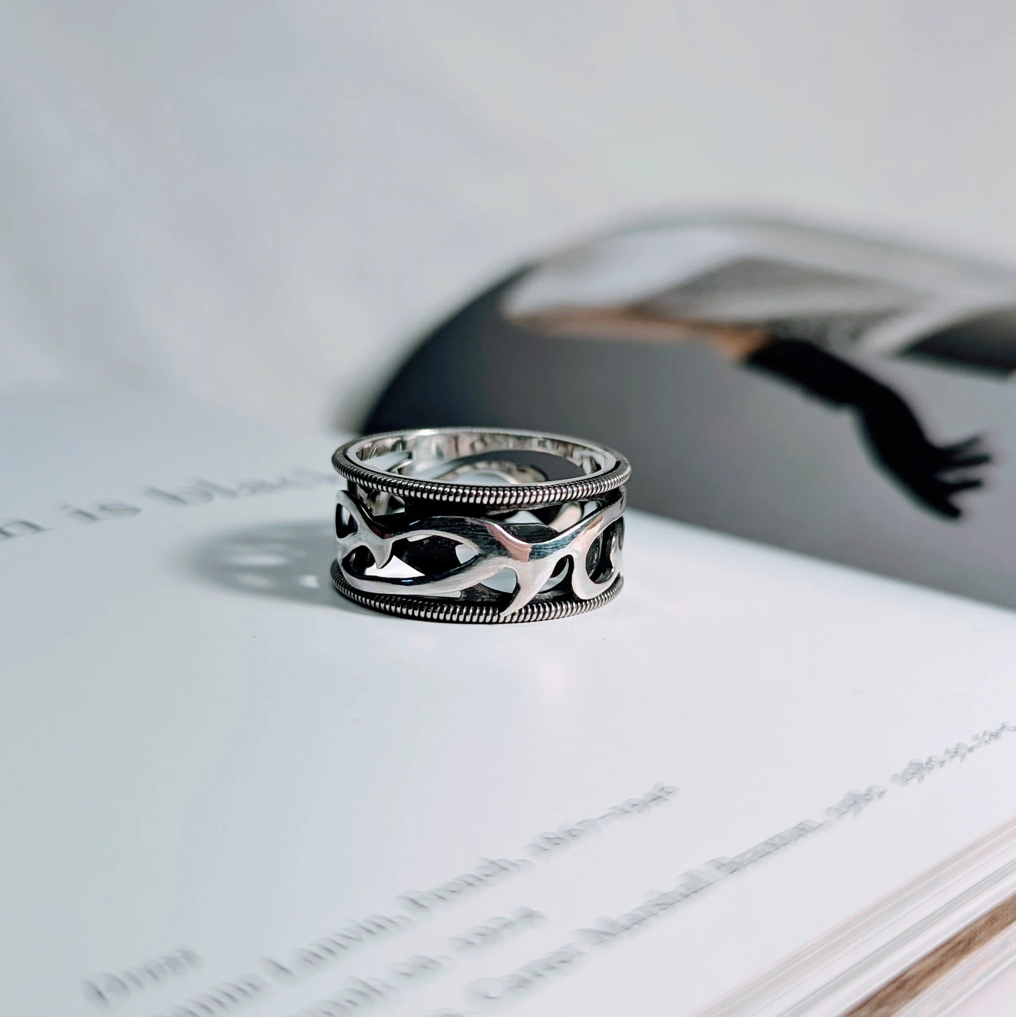 Sterling silver double cut out style band with tribal pattern featuring roped edges with a darkened background on the inside ring with high polished finishes