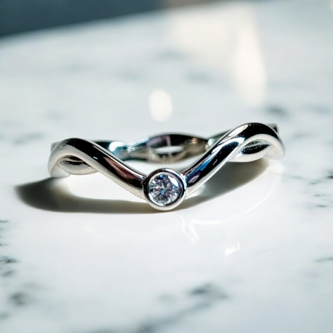 White gold ladies wedding band with a twisted curved band and a round brilliant diamond bezel set in the center