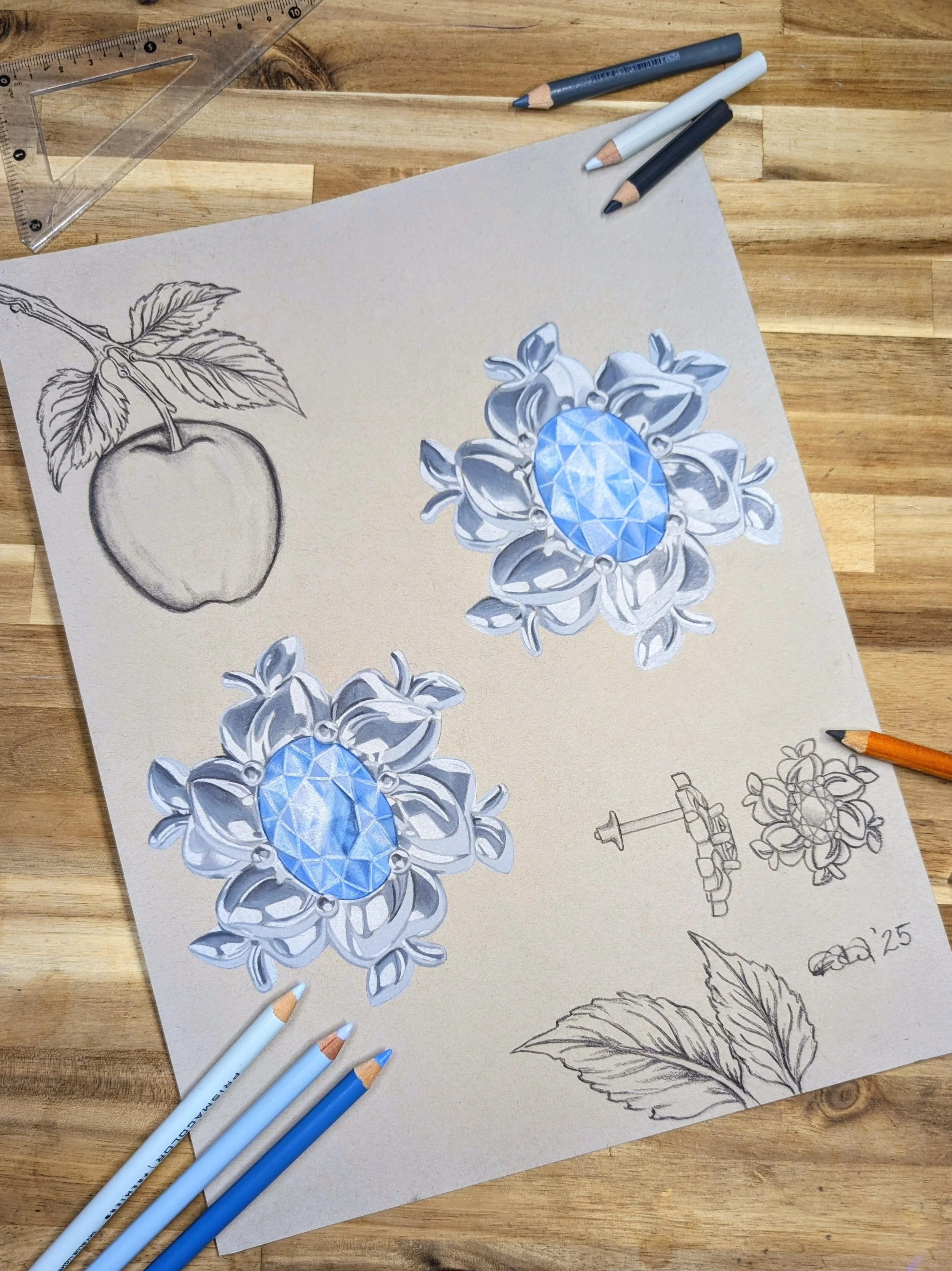 Drawing of a silver flower with a large blue gemstone at the center, sketch of an apple with leaves, and a sketch of a mechanism with a refined flower design, all on a beige sheet on a wooden table.
