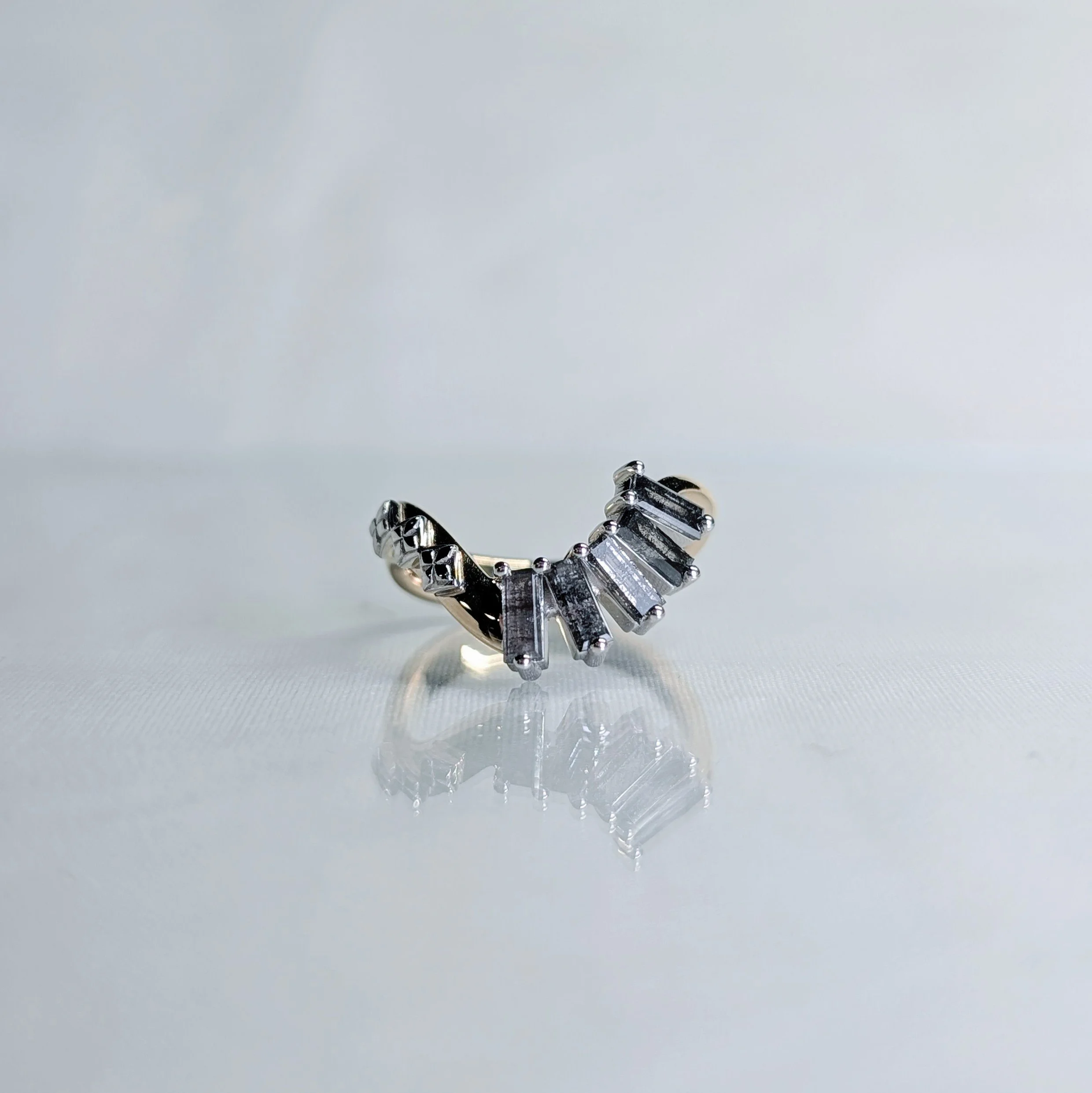 Asymmetrical curved yellow and white gold wedding band with five baguette cut salt and pepper diamonds with a geometric pattern on the left side