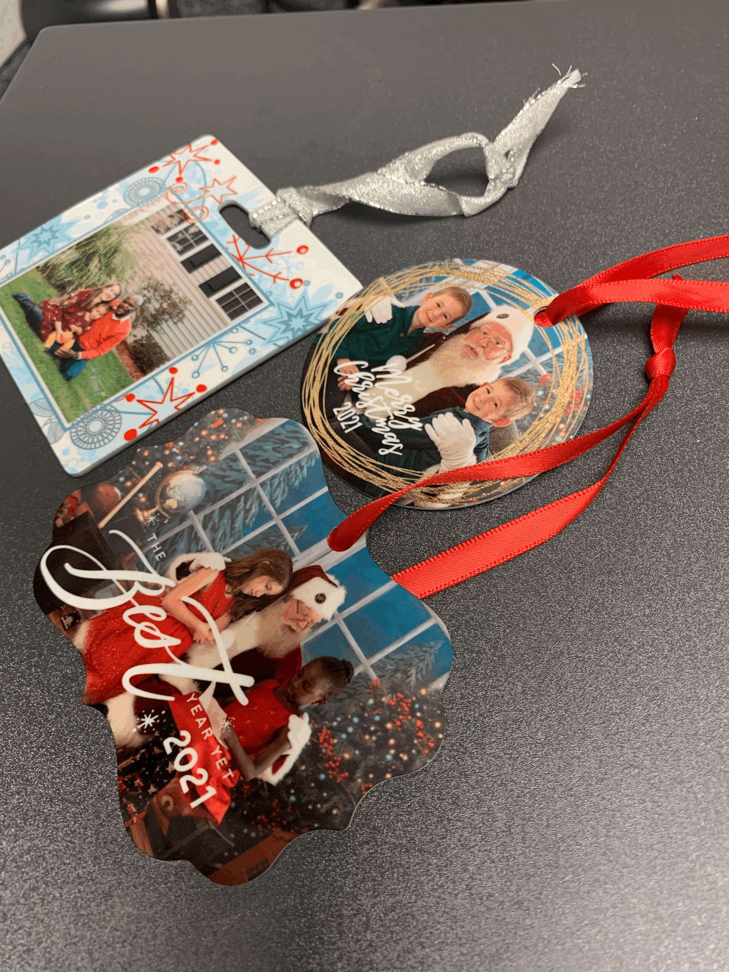 Three Christmas-themed photo ornaments with red and silver ribbons, featuring images of children with Santa Claus.