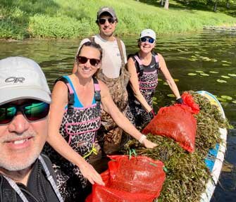 Dave, Alicia, Jimmy, Ann and a paddleboard topped with curly-leaf pondweed they removed from square lake.