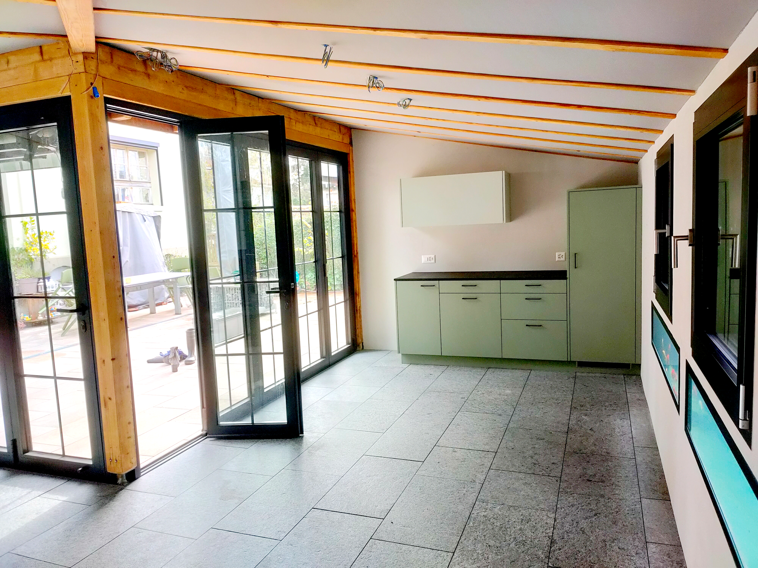 Umbau Gartenhaus, grüne Küche, Natursteinbelag, Verbindung innen und aussen, Berner Oberlang