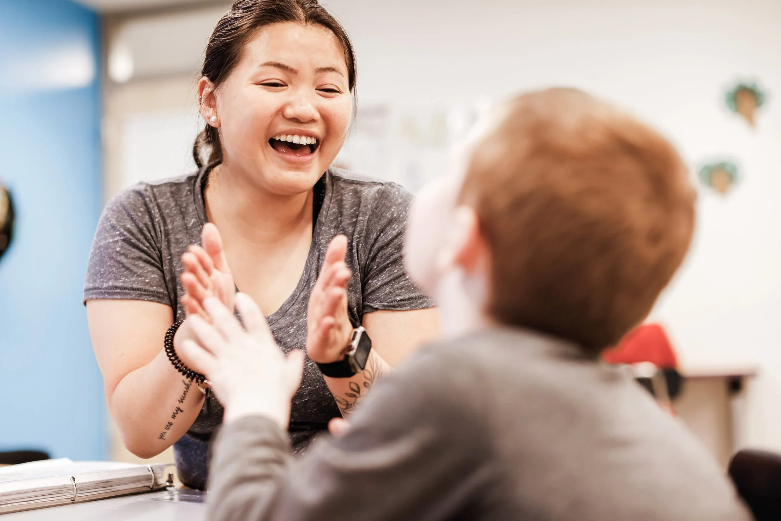 Crossroads Continuum staff member clapping hands with a child during a classroom activity focused on inclusive education.