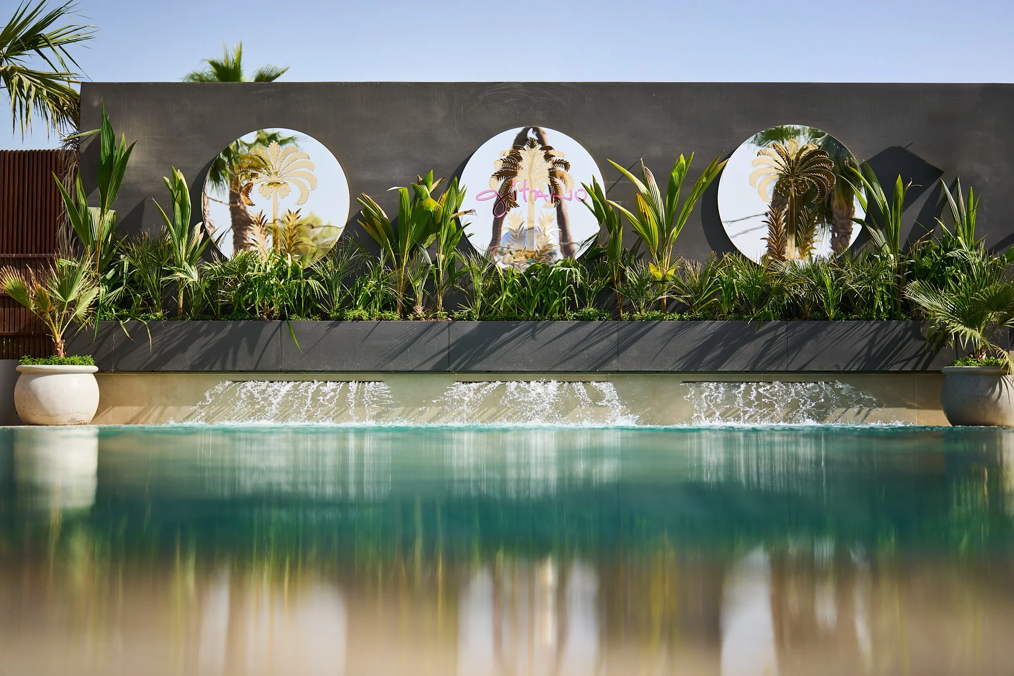 The entrance to GITANO DUBAI at J1 Beach, lined with palms and tropical greenery leading to a chic beachfront oasis.
