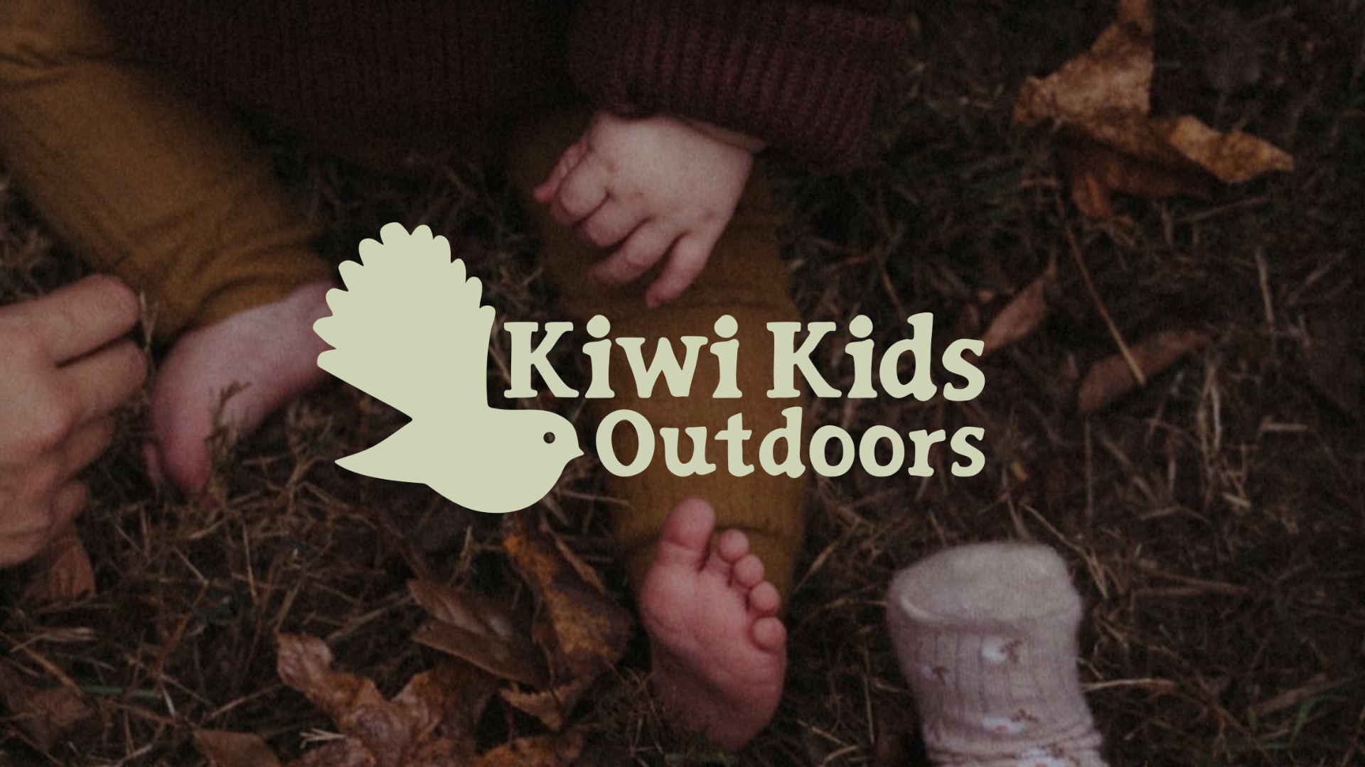 kiwi kids outdoors logo over baby playing in nature