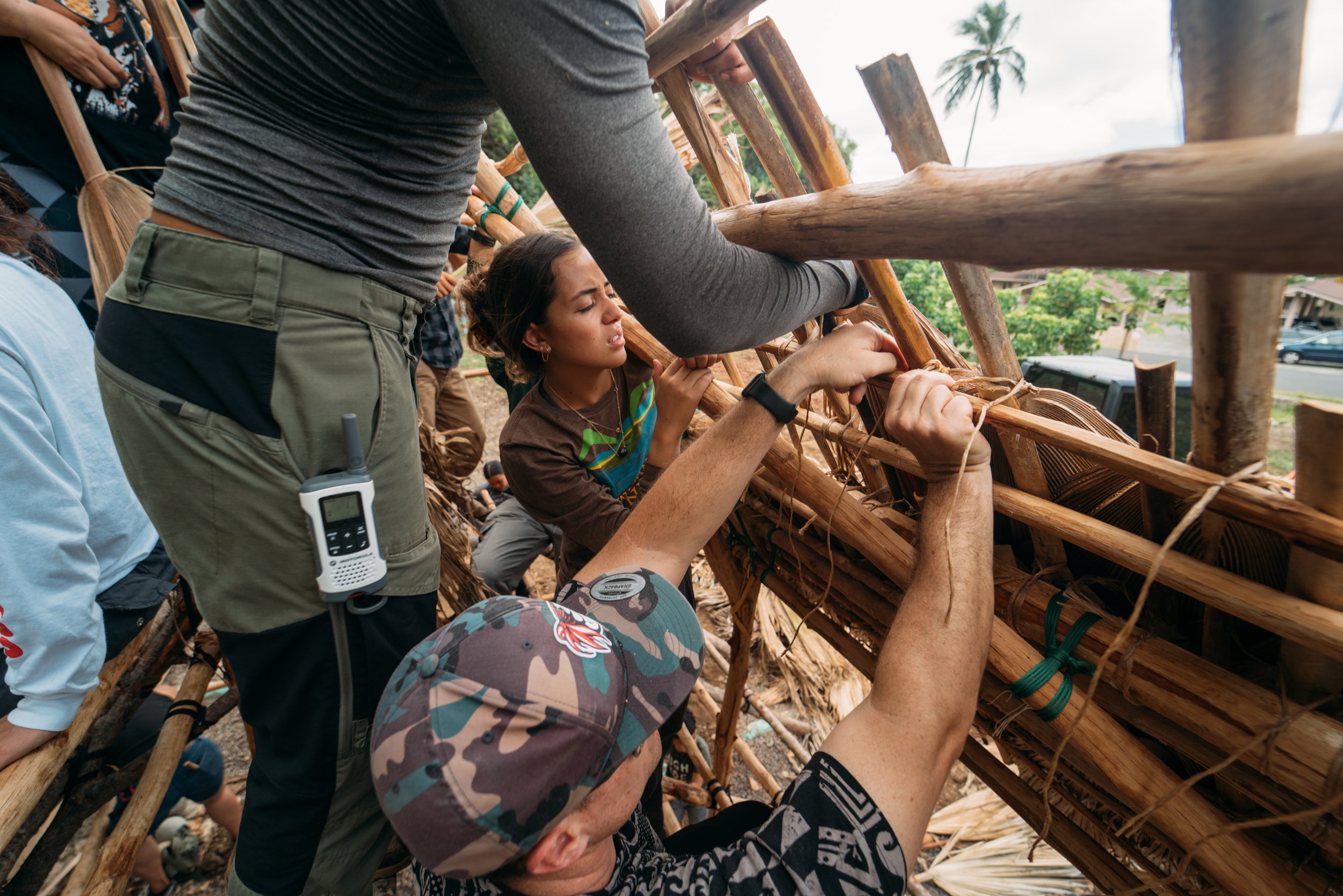 Maunawila Opio Thatching Leaves to the Hale Roof.jpg
