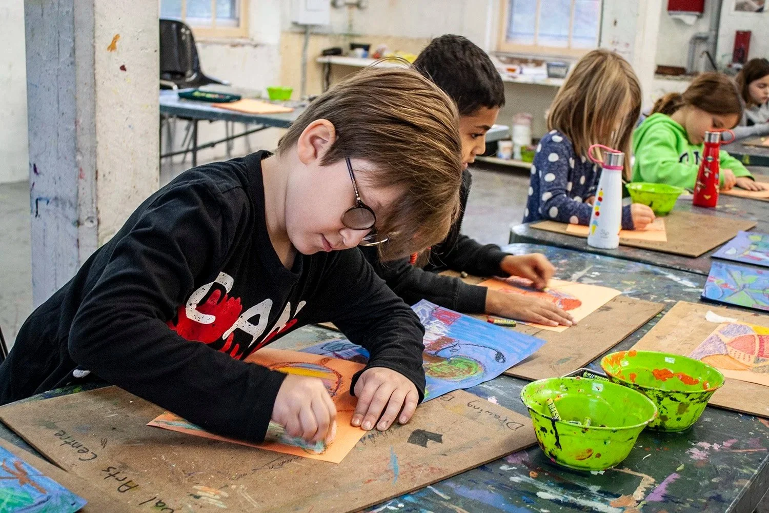 Children working on colourful paintings and drawings in art studio 