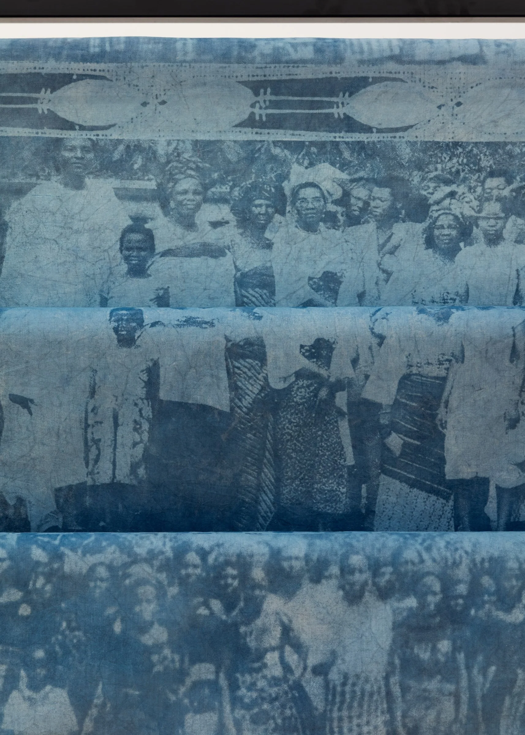 Close up of blue, hand-dyed fabric displaying an archival image of a group of Nigerian women. 
