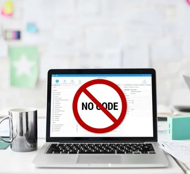 A computer sitting on a desk with other office paraphernalia around, and on the computer screen are the words NO CODE in all capitals but with a circle around it and a red line through it.