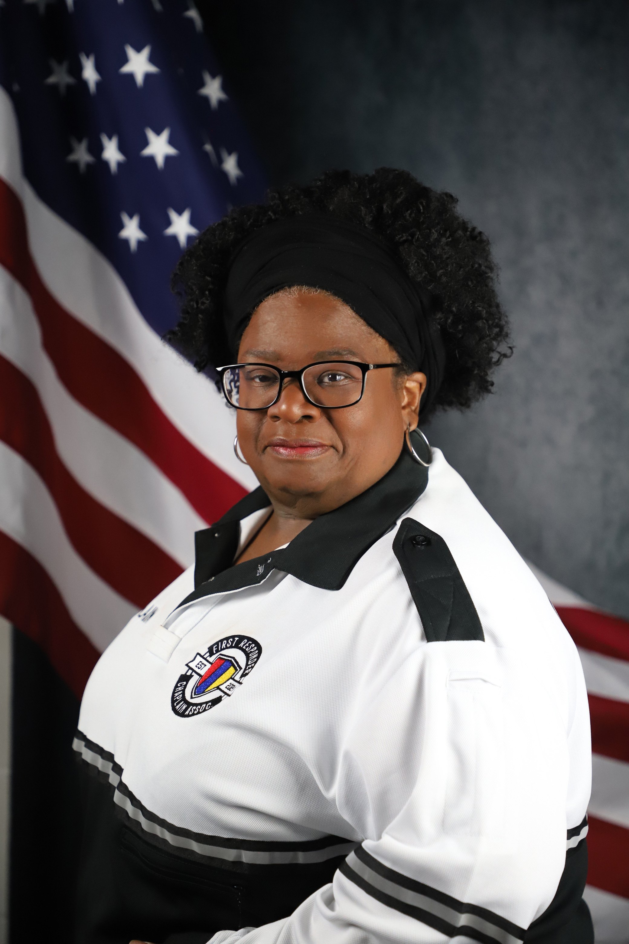 Woman in uniform with an American flag in the background.