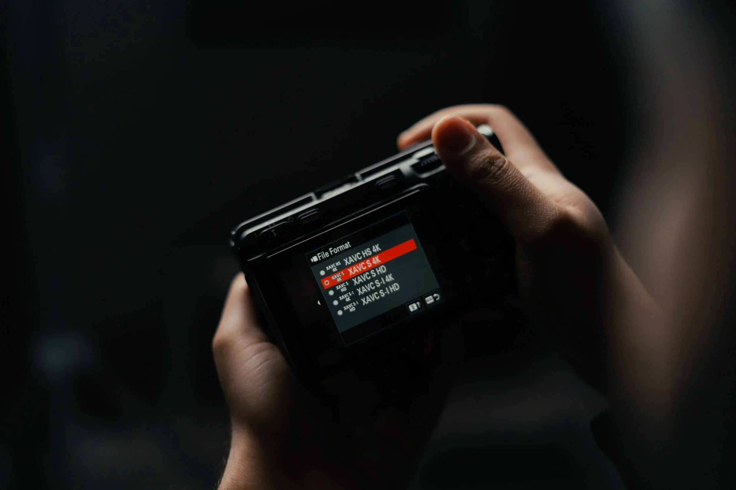 hands holding sony fx30 with menu system on the camera screen