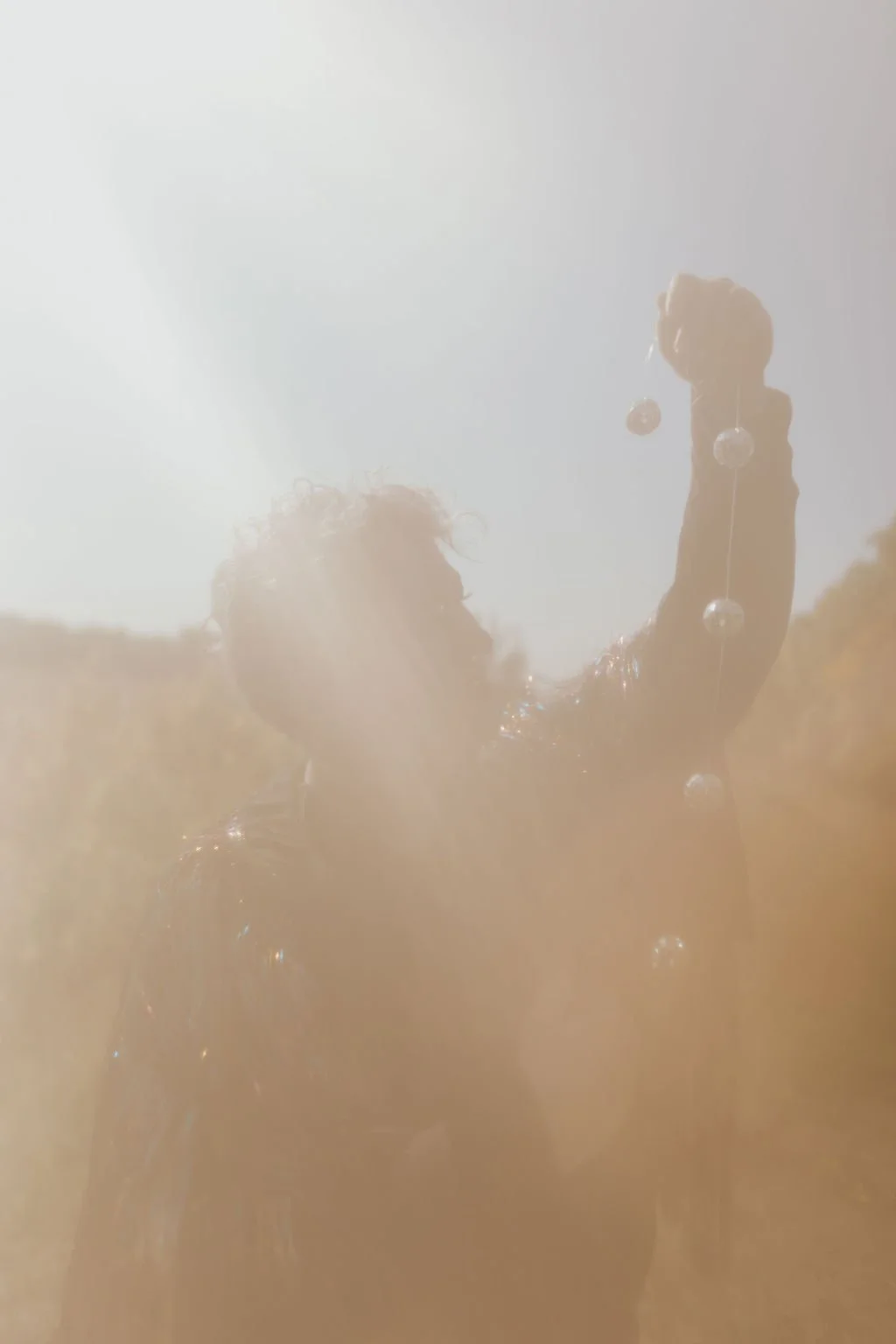 Silhouetted person holding a string with reflective spheres in bright sunlight