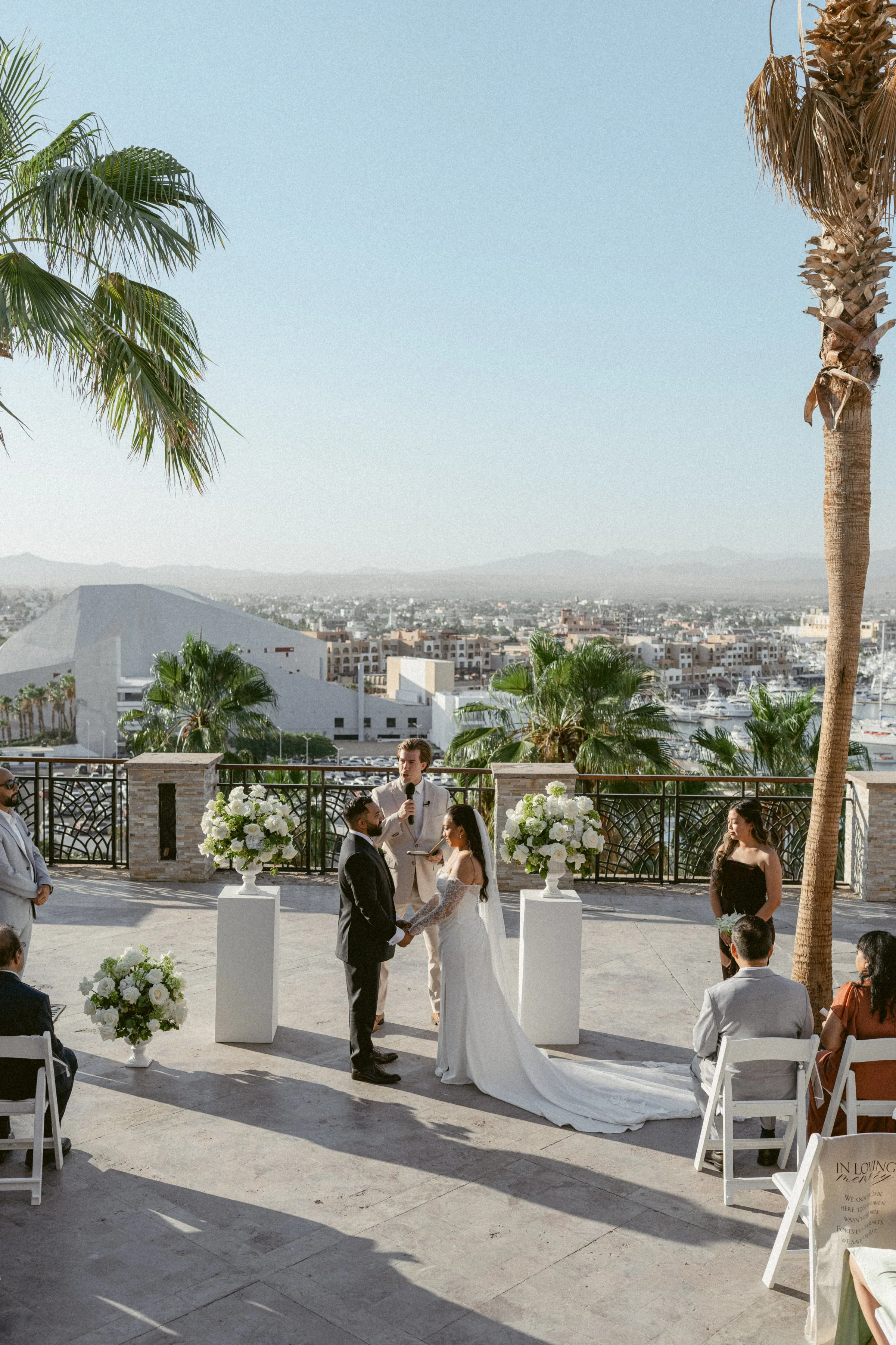 Outdoor wedding ceremony in Mexico with white florals overlooking the coastline.