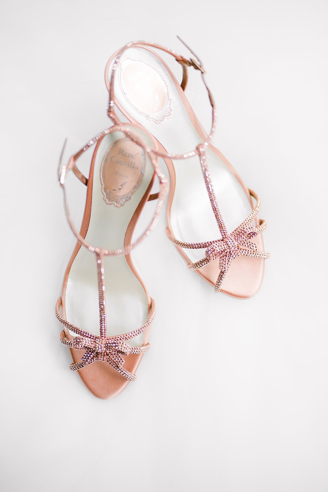 rene caovilla bridal shoes with pink jewel encrusted bows stand on white background for vancouver wedding