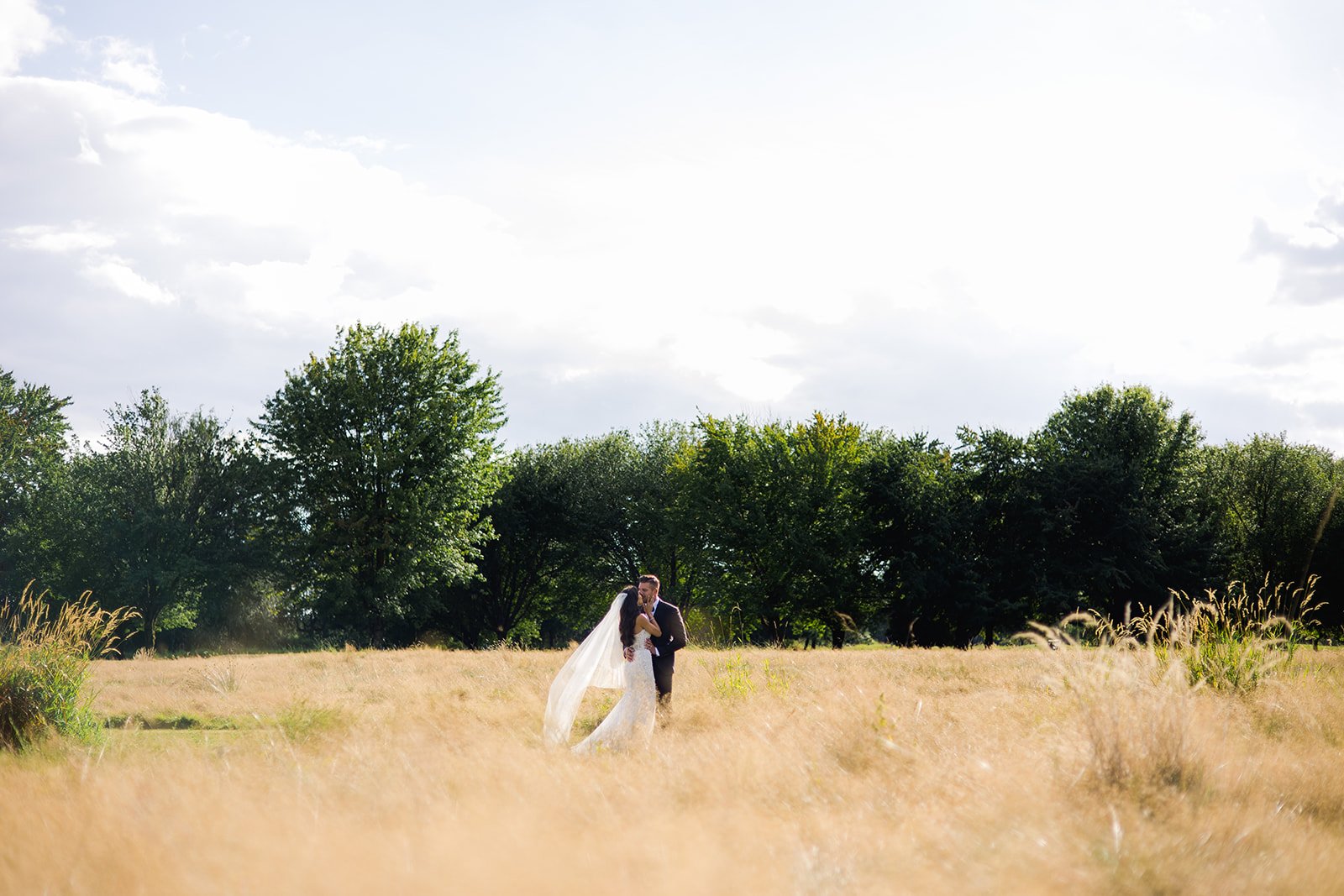 bridal veil wafts in wind amid long romantic grass during photoshoot in Vancouver British Columbia 
