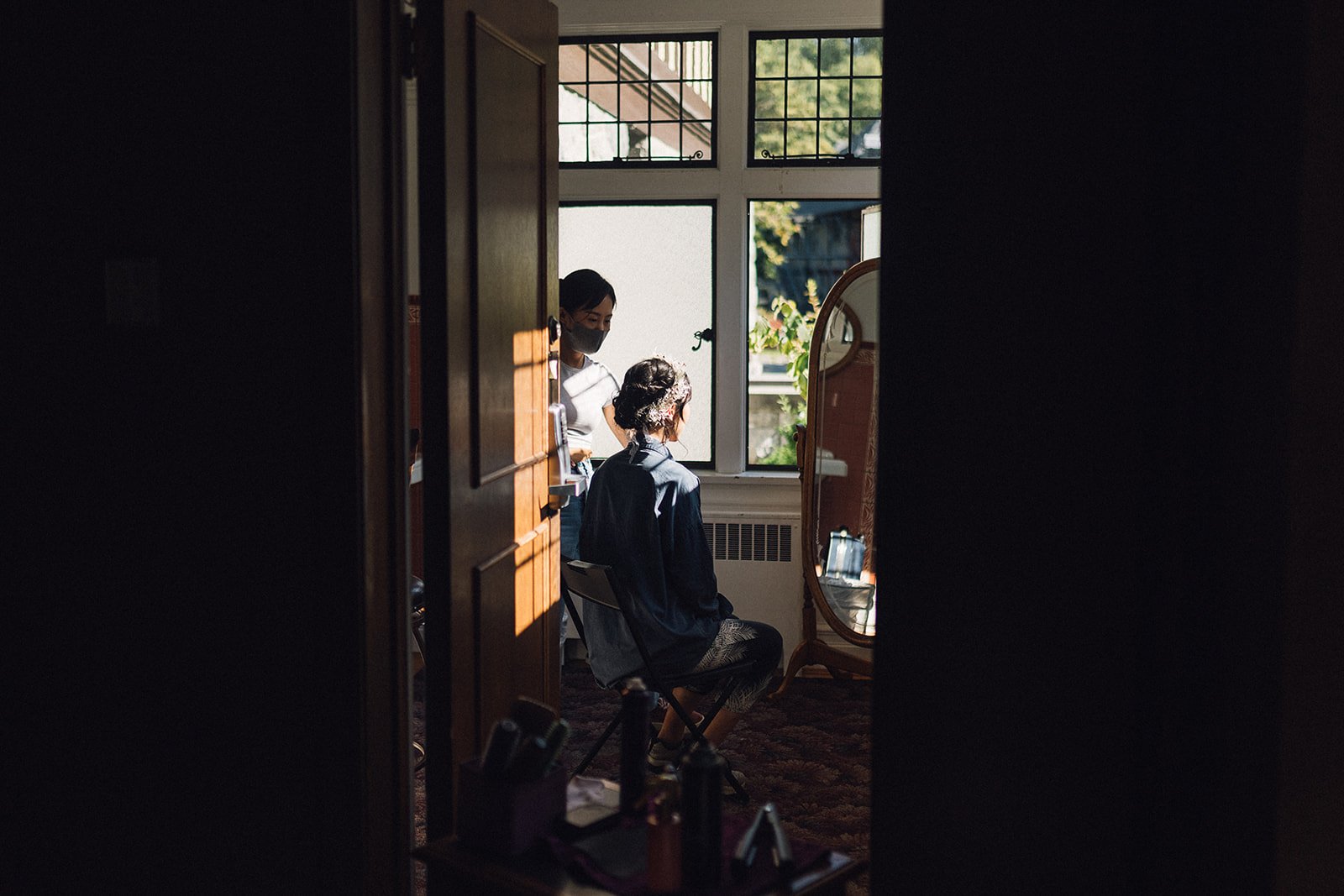 Bride looking in the mirror while getting her hair and make up done on her wedding day at Cecil Green Park House in Vancouver, BC.