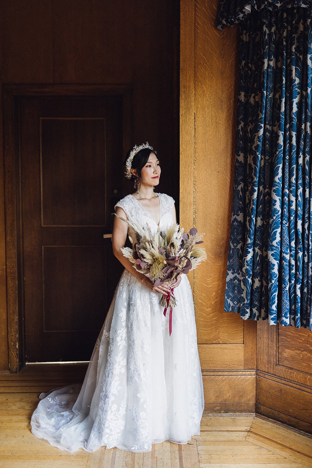 A bridal portrait of an Asian bride holding her pampas grass, fall-inspired wedding gown on the morning of her wedding at Cecil Green Park House.