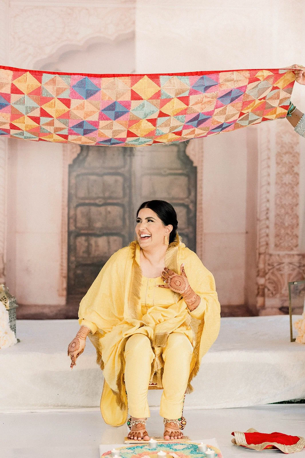 Sikh woman sitting in a yellow outfit during her Maiyan ceremony in Vancouver, BC.