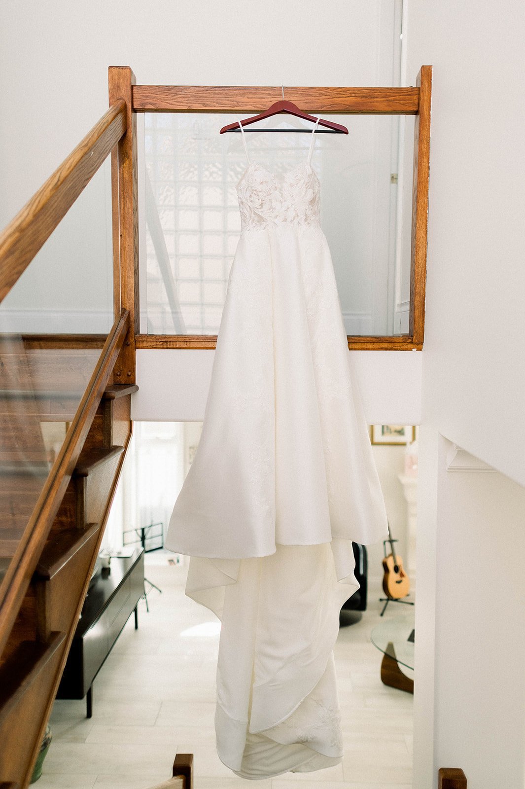 White lace wedding dress hangs from staircase in hart house wedding in Vancouver