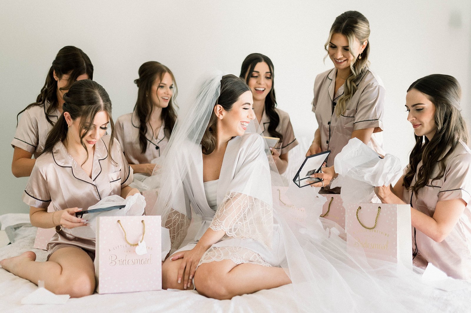 Bridesmaids give gifts to bride on comfy bed during the wedding morning for a hart house wedding in Vancouver BC. 
