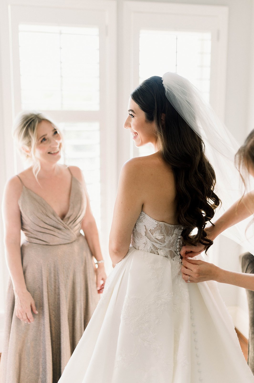 Bridesmaid watches jealously, feigning a smiles as the bride dons her wedding dress for her big day at Hart House in Vancouver BC