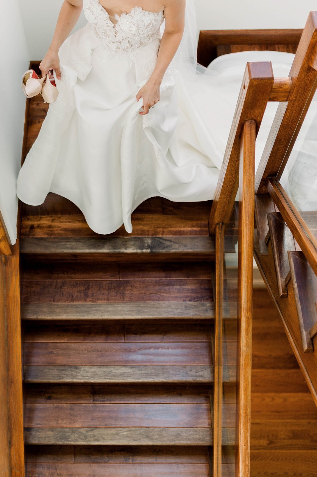 Bride descends staircase, holding up her wedding dress to reduce tripping hazards, as she makes her way to hart house wedding. Photographed by beautiful life studios