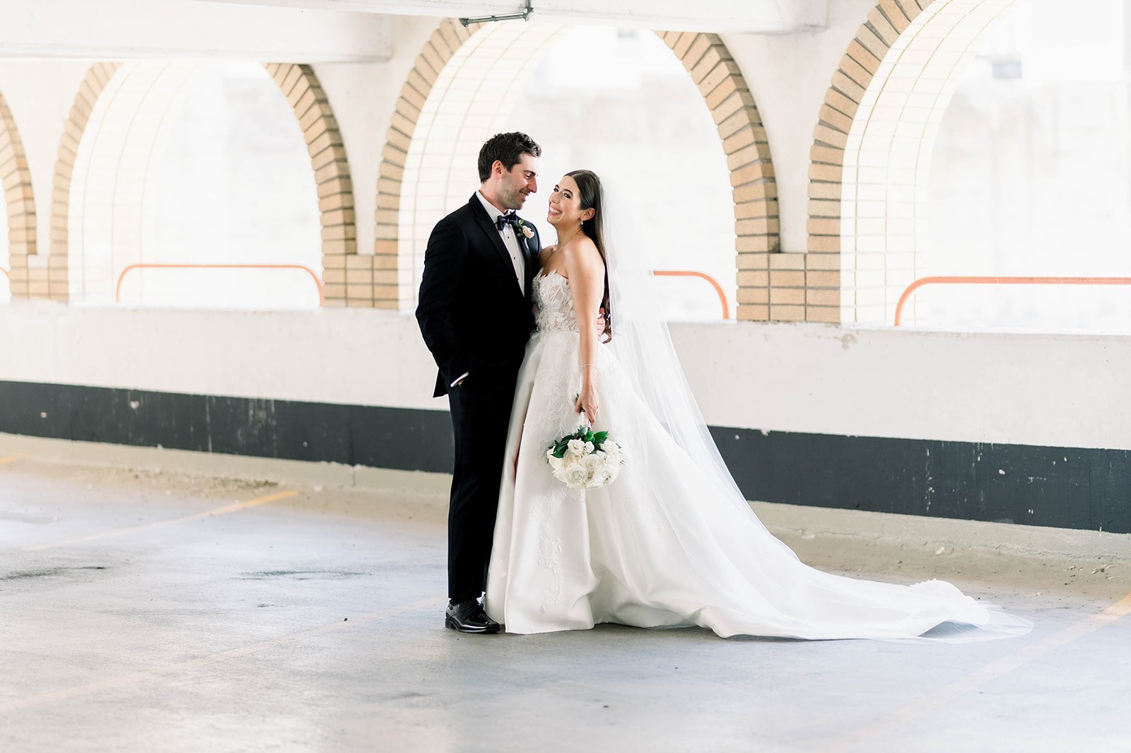 Groom makes bride laugh in ascetically pleasing parking garage before hart house wedding. 
