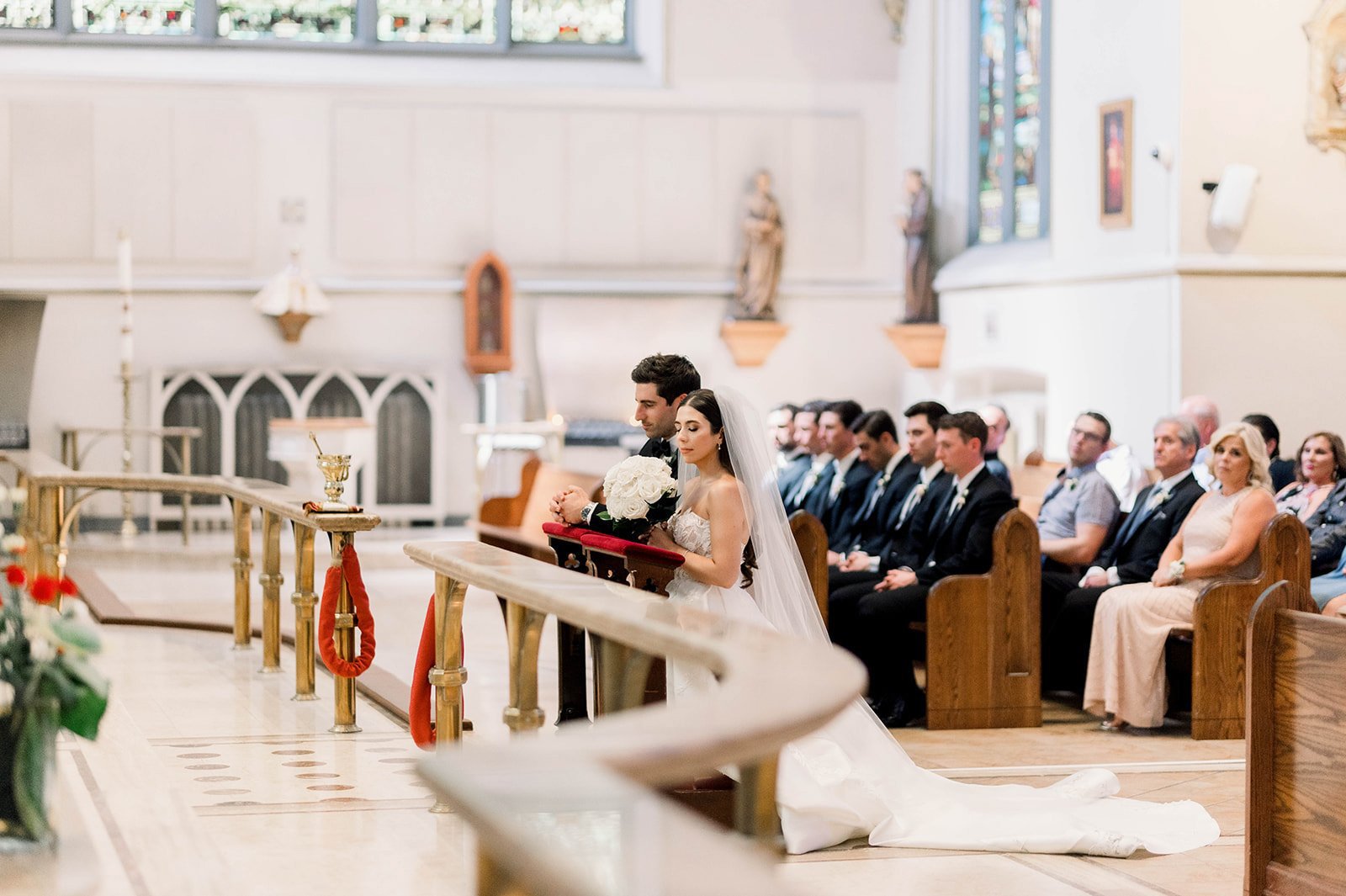 Bride and groom kneel at hassock in catholic ceremony in Vancouver BC